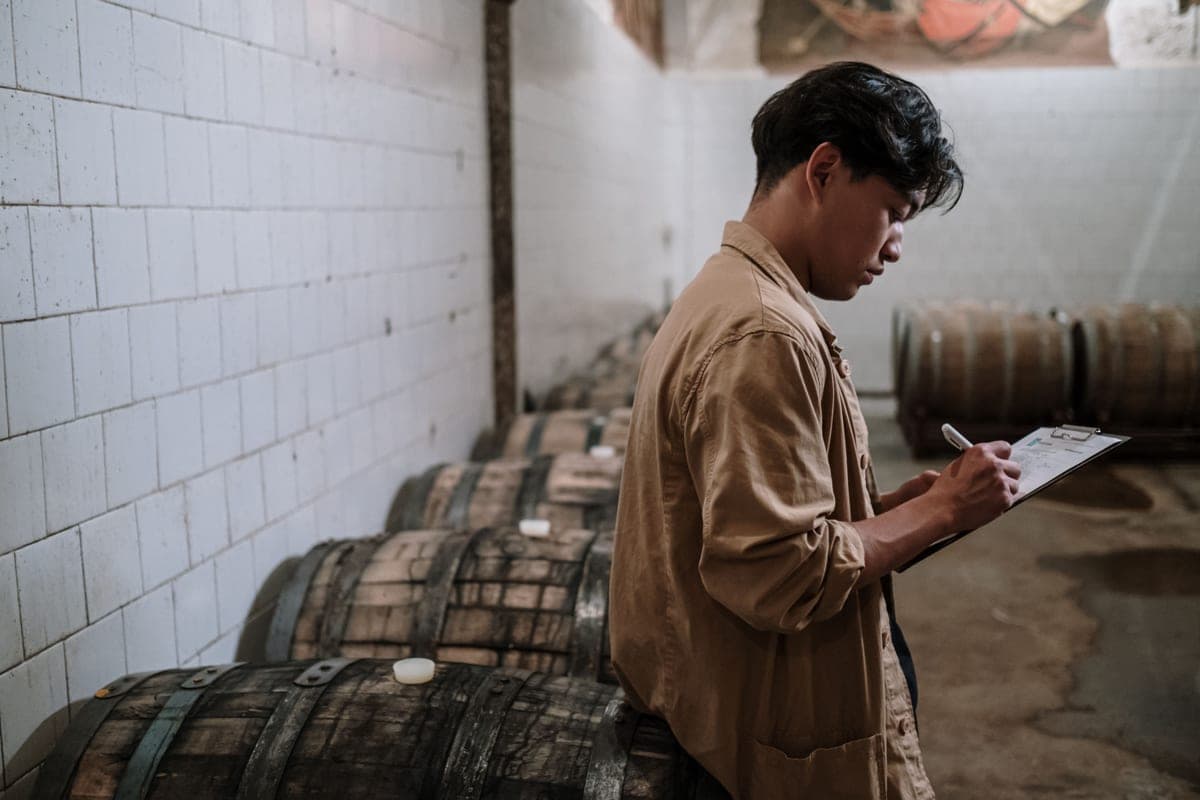 A brewer taking notes beside brewing equipment
